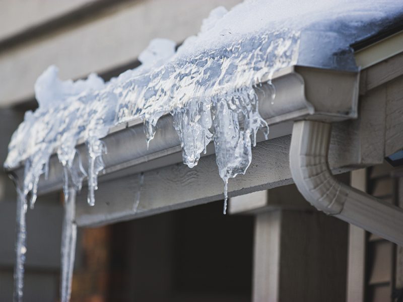 Icicles hanging from frozen ice filled gutter close up picture